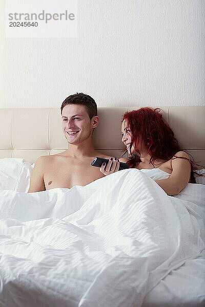 Glückliches junges Paar  das im Bett liegend fernsieht  Nahaufnahme