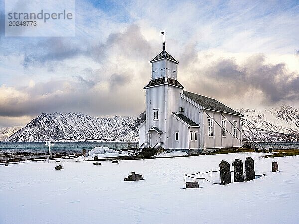 Gimsøy Kirche mit Friedhof  hinten schneebedeckte Berge  Winter  Gimsøya  Lofoten  Norwegen  Europa