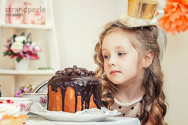 Faszinierendes kleines Mädchen betrachtet nachdenklich den Kuchen