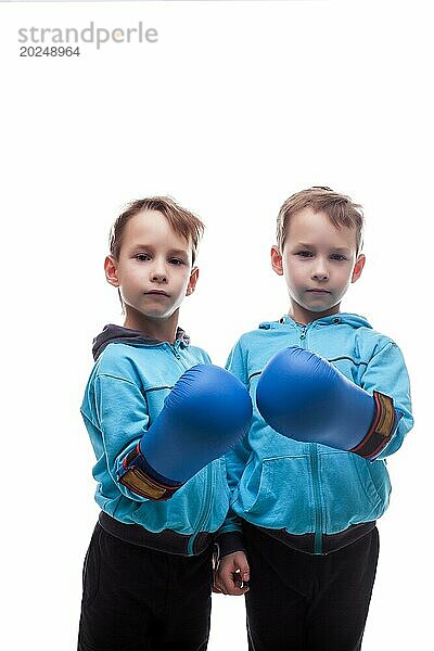 Zwei ernste Zwillinge posieren mit Boxhandschuhen  vor weißem Hintergrund