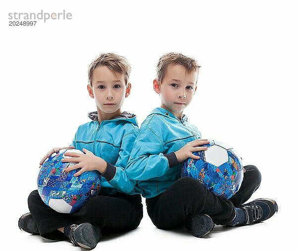 Bild von amüsanten Zwillingsbrüder posieren mit Bällen  vor weißem Hintergrund