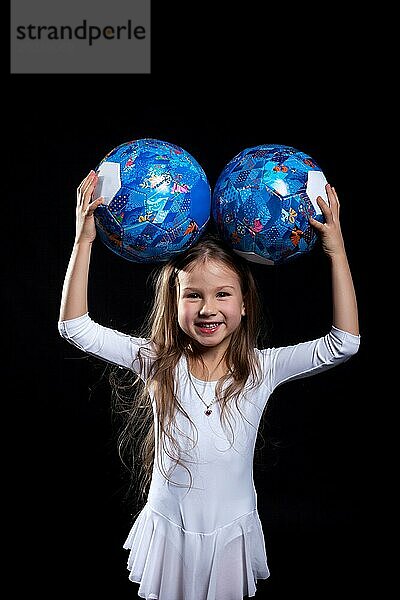 Glückliches kleines Mädchen posiert mit Gymnastikbällen  Nahaufnahme