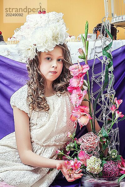 Luxuriöses kleines Mädchen posiert mit Blumenarrangements