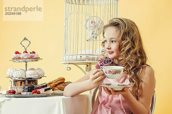 Bild von zufriedenes kleines Mädchen trinkt Tee mit Kuchen im Studio