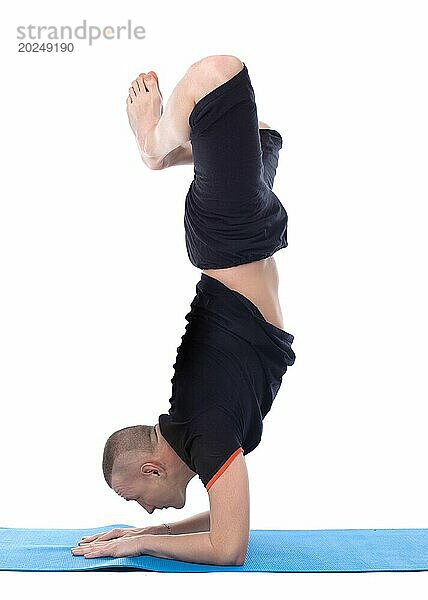 Bild von ruhigen Mann macht Yoga Handstand im Studio