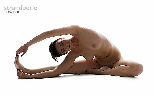 Studioaufnahme einer lächelnden nackten Frau beim Yoga  vor weißem Hintergrund