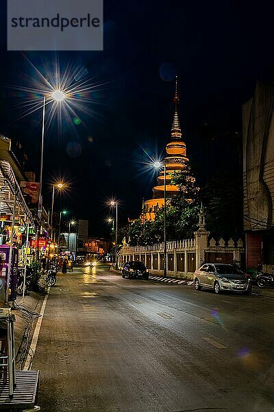 Ruhige nächtliche Stadtstraße mit einem Tempel im Hintergrund unter klarem Himmel in Chiang Mai  Thailand  Asien