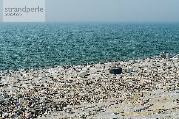 Weite Sicht auf eine felsige Küste in Südkorea  die mit Abfall und einem Reifen verschmutzt ist