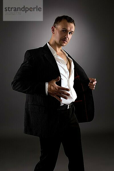 Striptease. Bild eines attraktiven Mannes im Anzug mit Streifen