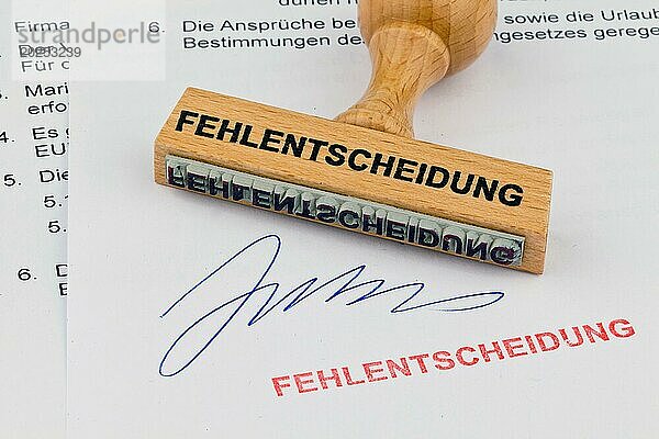 Ein Stempel aus Holz liegt auf einem Dokument. Aufschrift Fehlentscheidung