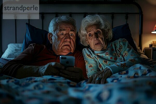 Ein älteres Ehepaar liegt im Ehebett in ihrem Schlafzimmer und schaut besorgt  verängstigt  verunsichert auf ein Smartphone  Symbolbild für Betrug an Senioren  Enkeltrick  Schockanrufe  herausgabe von persönliche Daten wie Passwort  Bankverbindung  Wohnadresse  Medienkompetenz  KI generiert  AI generiert  AI generated