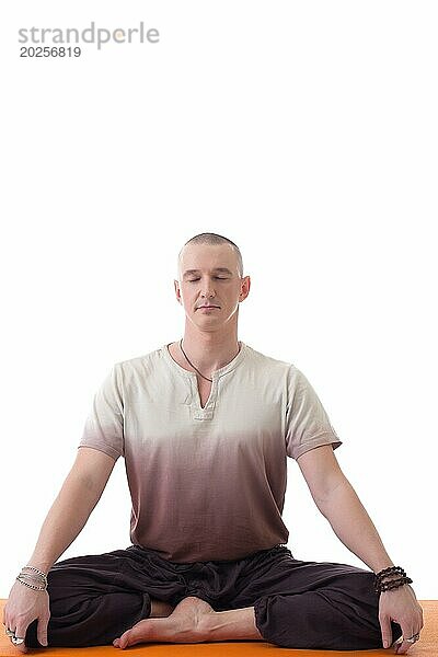 Attraktiver meditierender Mann in Lotushaltung  vor weißem Hintergrund