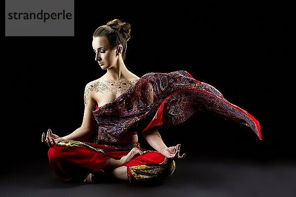 Schöne ruhige Frau meditiert im Lotussitz und ihr Sari fliegt