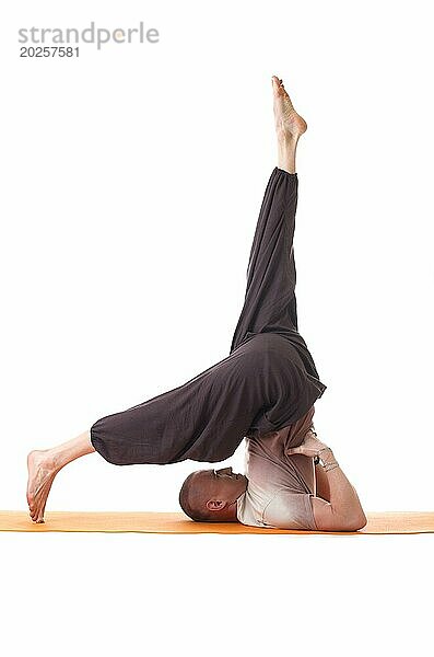 Studioaufnahme eines flexiblen  sportlichen Mannes beim Yoga  vor weißem Hintergrund