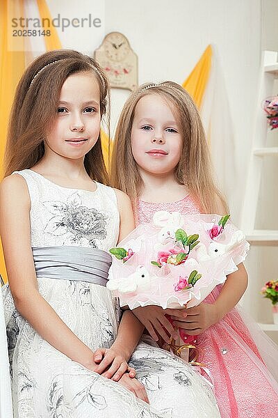 Niedliche kleine Schwestern posieren mit einem Blumenstrauß aus Spielzeug  Nahaufnahme
