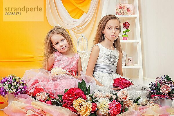 Zwei schöne kleine Schwestern posieren in eleganten Kleidern
