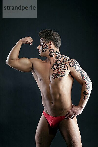 Bild von muskulösen Mann posiert mit Muster auf Körper  auf grauem Hintergrund