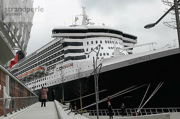 Ein großes Kreuzfahrtschiff Queen Mary 2  am Dock  Menschen spazieren auf dem Steg  Hamburg  Hansestadt Hamburg  Deutschland  Europa