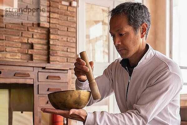 Ein junger asiatischer Erwachsener  der tief in die Praxis der Meditation vertieft ist  sitzt gelassen inmitten einer Atmosphäre der Ruhe und Harmonie  umhüllt vom reichen Wandteppich der tibetisch buddhistischen Tradition