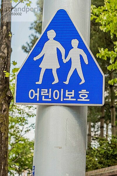 Ein blaues Fußgängerübergangsschild mit der Silhouette zweier Kinder  die sich an den Händen halten  in Daejeon  Südkorea  Asien