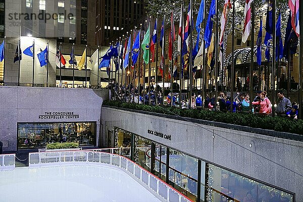 Menschen betrachten die Eislaufbahn im Rockefeller Plaza  umgeben von Flaggen  Manhattan  New York City  New York  USA  Nordamerika