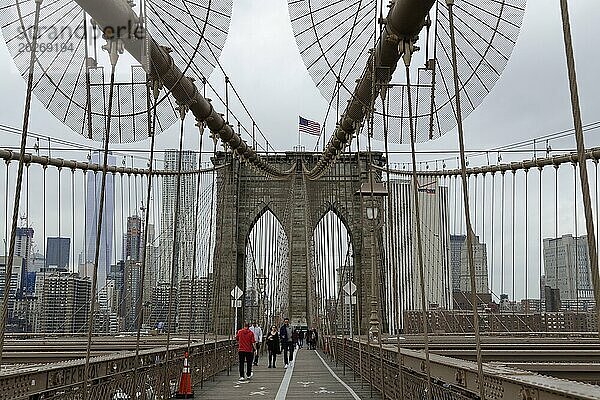 Brooklyn Bridge  Menschen gehen über eine berühmte Hängebrücke mit städtischer Silhouette im Hintergrund  Manhattan  New York City  New York  USA  Nordamerika