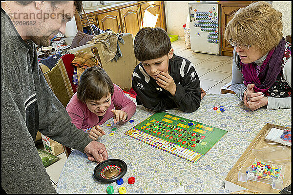 ASE – Sozialhilfe für Kinder. Nicolas und Clemence spielen mit ihrem Vater und Isabelle ein Brettspiel. NUR FÜR REDAKTIONELLE ZWECKE.