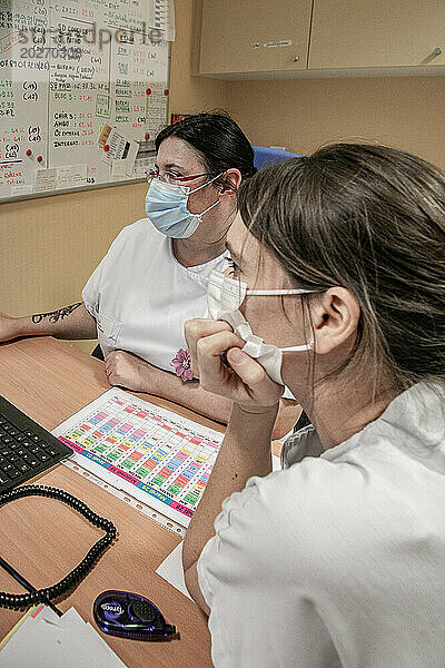 2 Krankenschwestern besprechen Patienten im Büro der Entbindungsstation.