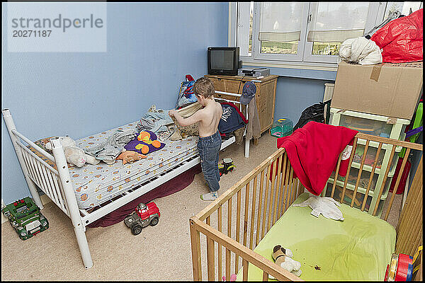 ASE – Sozialhilfe für Kinder. Morgan  5  kleidet sich allein wie ein Erwachsener in seinem Zimmer  in dem er mit seinem kleinen Bruder Maxence schläft. NUR FÜR REDAKTIONELLE ZWECKE.