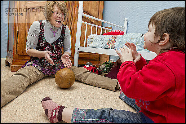 ASE – Sozialhilfe für Kinder. Isabelle spielt mit Sarah auf dem Boden des Jungenzimmers Ball. NUR FÜR REDAKTIONELLE ZWECKE.