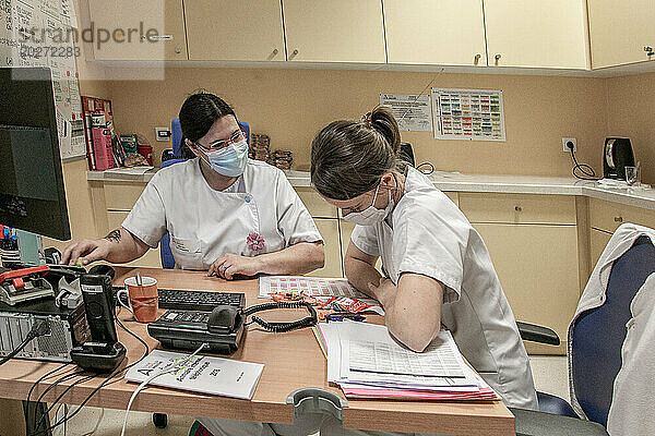 2 Krankenschwestern besprechen Patienten im Büro der Entbindungsstation.