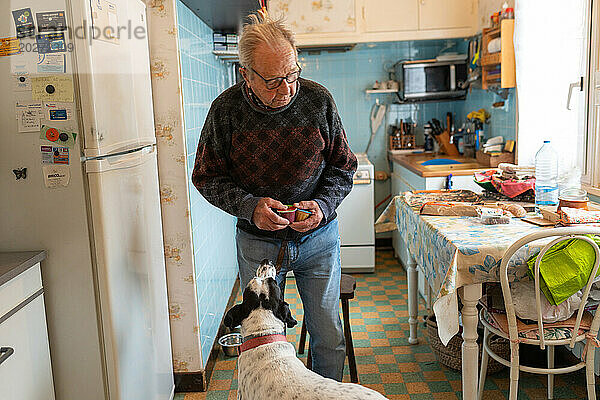 Einsamkeit eines 90-jährigen Seniors  der allein mit seinem Hund lebt und eine Mahlzeit zubereitet.