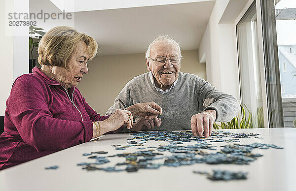 Glücklicher Mann und Frau  die zu Hause ein Puzzlespiel spielen
