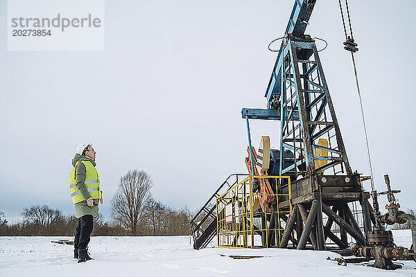 Ingenieur untersucht Bohrturm am Ölförderfeld im Winter