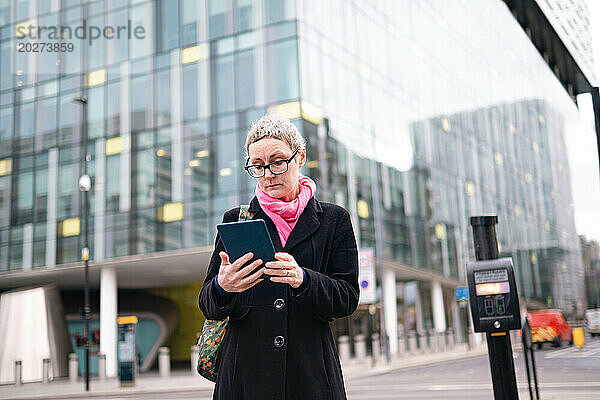 Mature businesswoman using tablet PC on street