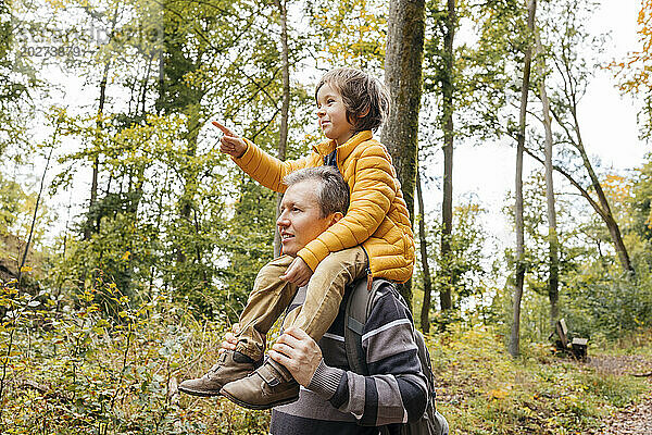 Vater trägt Sohn auf Schultern im Herbstwald