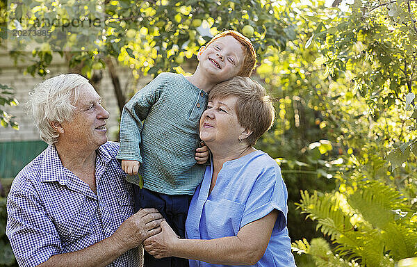 Smiling boy having fun with grandparents in garden
