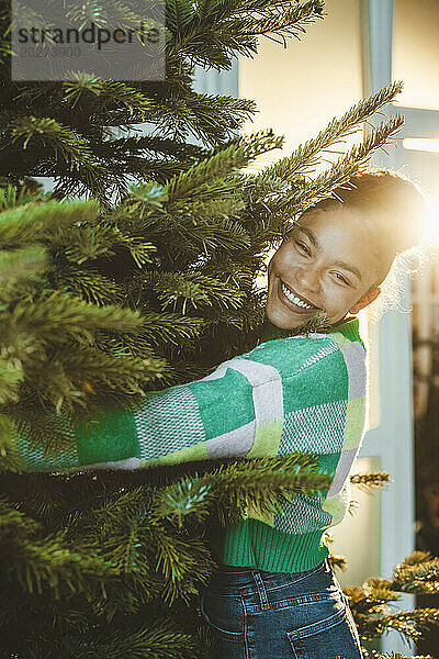 Lächelnde Frau umarmt den Weihnachtsbaum