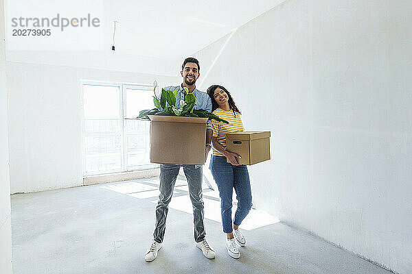 Glückliches junges Paar steht mit Kartons im neuen Zuhause