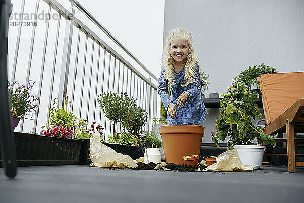 Lächelndes Mädchen bei der Gartenarbeit auf dem Balkon