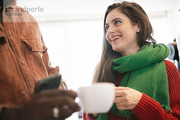 Glückliche Frau mit Schal neben Mann im Café
