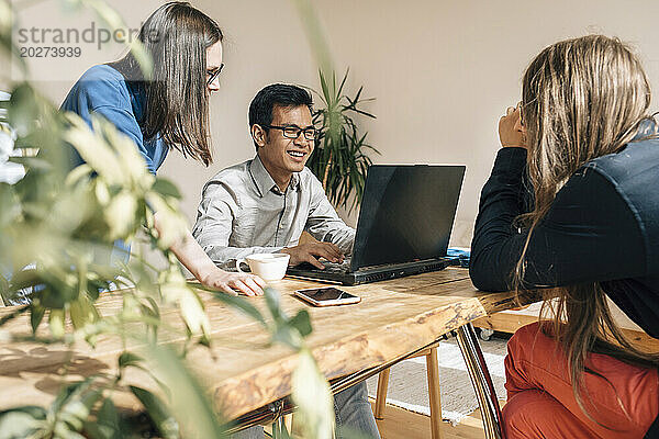 Lächelnder IT-Techniker diskutiert mit Kollegen im Kreativbüro