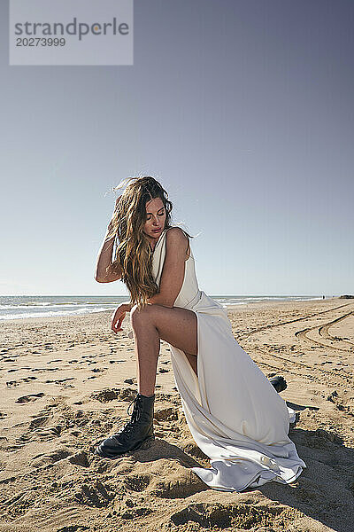 Schöne junge Frau im Hochzeitskleid am Strand