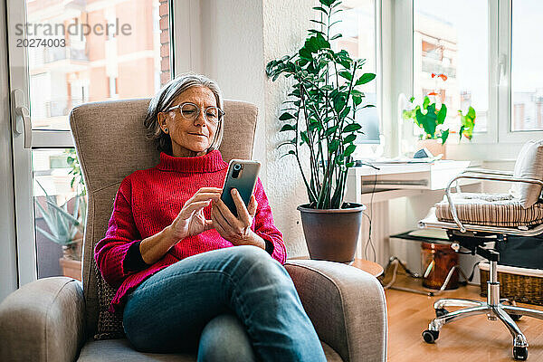 Reife Frau benutzt Smartphone zu Hause