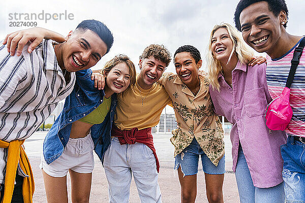 Gruppenfoto glücklicher junger Freunde in bunter Kleidung  die in die Kamera lächeln