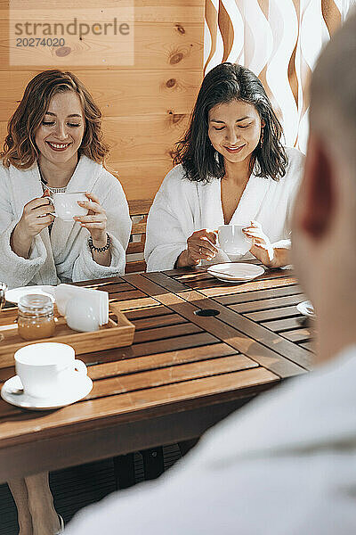 Smiling friends having tea at sauna