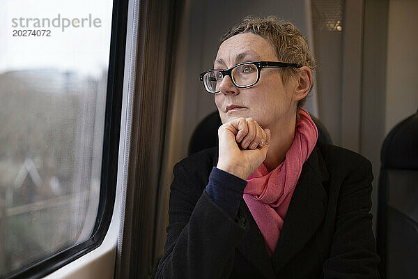 Thoughtful businesswoman wearing eyeglasses and traveling in train