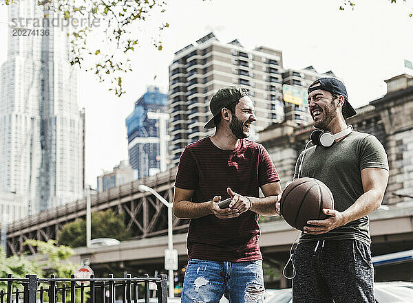 Happy young friends laughing together in city