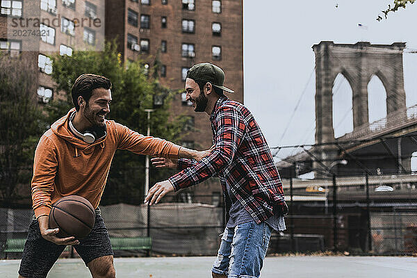 Junger Mann spielt Basketball mit Freund am Hof ??in der Stadt