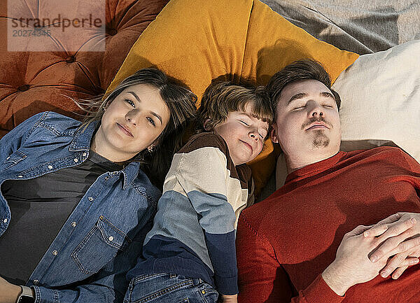 Smiling woman with family relaxing on bed at home